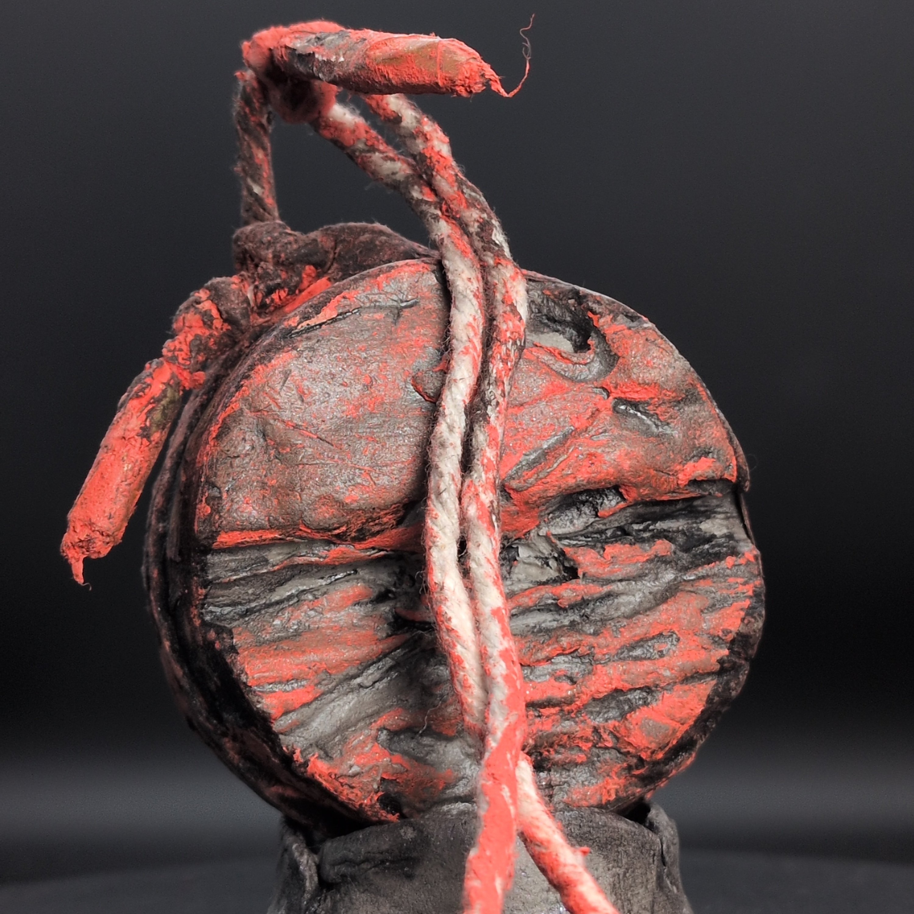 Handmade clay spirit vessel with red and charcoal disc face and looped rope cord